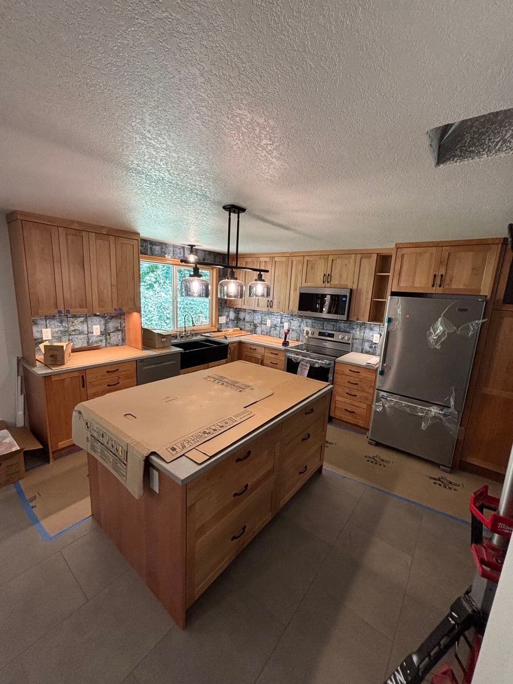 Modern kitchen with wooden cabinets, stainless steel appliances, and a large island under pendant lights.