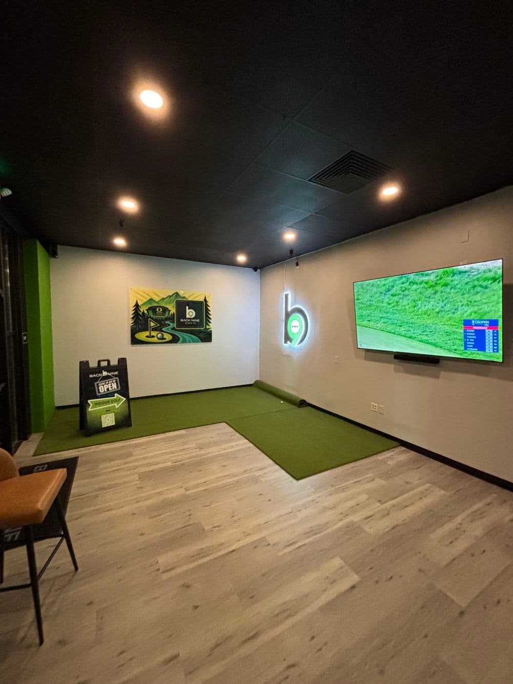 Indoor golf simulator room with putting green, TV, and golf-themed decor. Cozy and modern design.