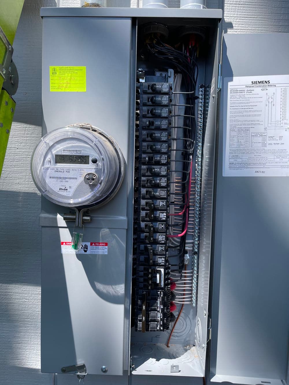 Siemens electrical panel with circuit breakers and smart meter, mounted on a wall.