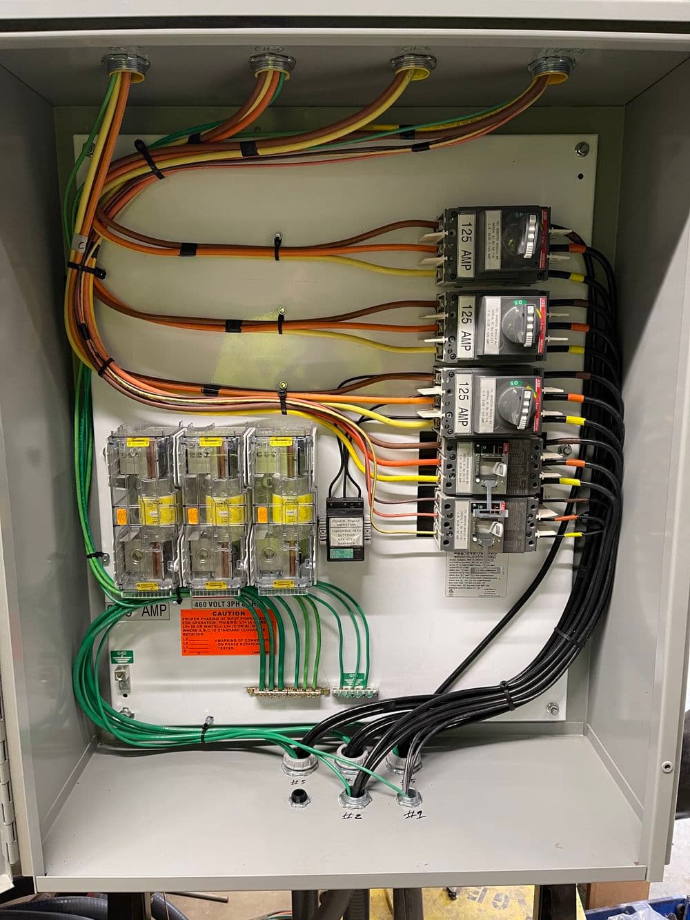 Electrical panel with circuit breakers, fuses, and colorful wiring for power management.