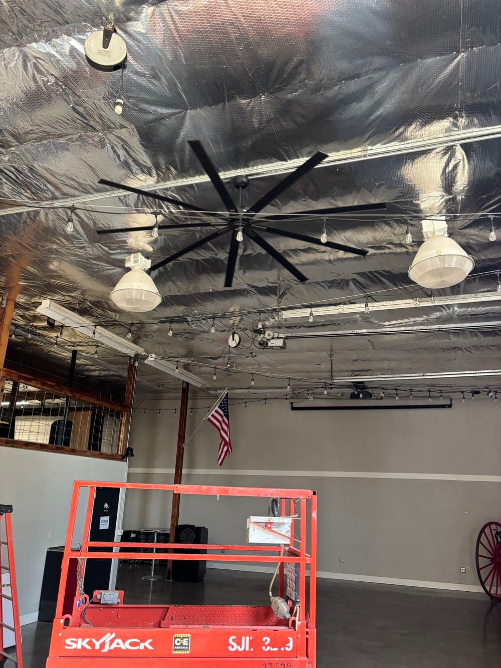 Large industrial ceiling fan with lights in a spacious room, featuring a scaffolding platform.